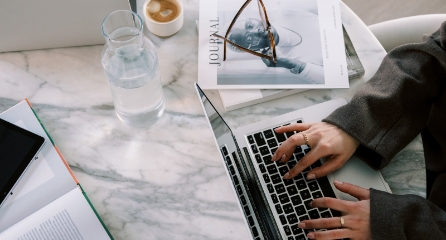 Overhead of hands typing on a computer keyboard.